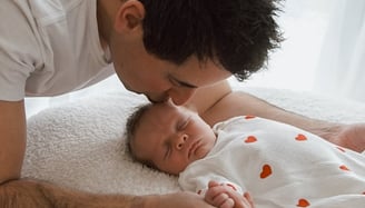 a man kissing a baby in a bed