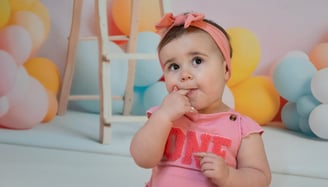 a baby girl in a pink shirt and a headband