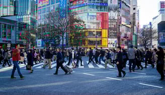 a group of people walking across a busy street