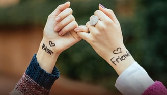 a woman's hand with "best" written on the wrist intertwined with another hand with "friends" written