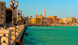 a Bari city street with a bridge and a boat in the water