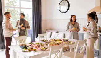 a group of people standing around a table with food