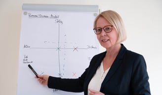a woman in a business suit is holding a pen and pointing at a white board