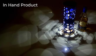 Jack Daniel’s metal packaging casting patterned light beside a whiskey bottle.