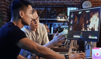 two men sitting at a computer screen and creating video with AI software