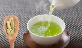 a teapot with a cup of coleus tea and a wooden spoon with dried coleus leaves