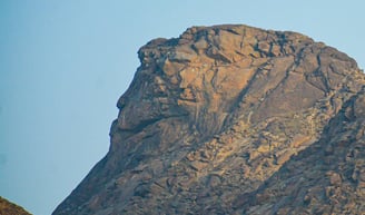 a bird flying over a mountain with a blue sky
