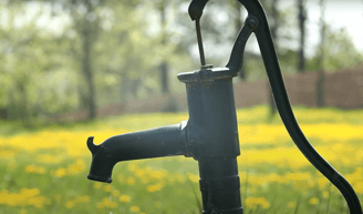 Image of a brass well faucet in a meadow