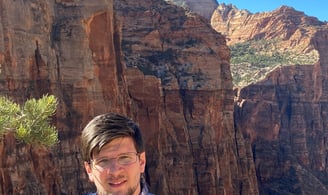 a man standing on a mountain top with a mountain in the background