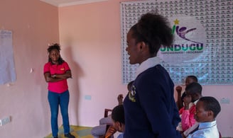 a woman standing in front of a classroom with a group of children