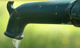 Rustic green outdoor faucet with water flowing