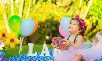 Petite fille assise dans un jardin sourit et regarde en haut - Micro-crèche ou assistante maternelle