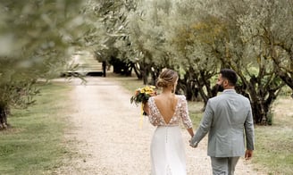 South of France wedding photographer cost — newlyweds walking through olive tree path