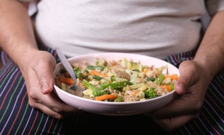 a person holding a bowl of food with a spoon and fork