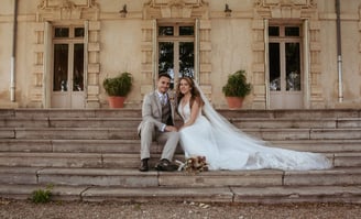 belle photographie des mariées assis sur les marches du château