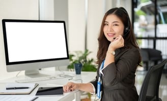 customer support service agent with a headset sits at her desk in the office