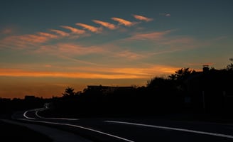 a  dark sunset scene of a road with a car on the horizon, old montauk highway