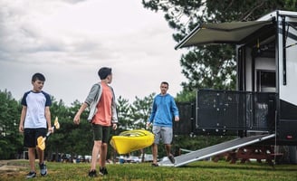a group of people walking around a trailer carrying a canoe