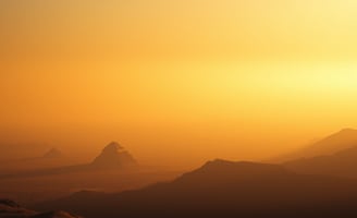 UniverseX - a person standing on a mountain top with a view of the sun setting