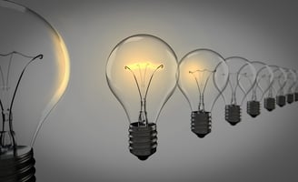 Row of lightbulbs with one glowing, symbolizing insight and breakthrough