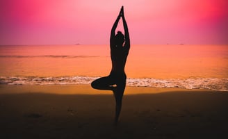 Silhouette of a woman practicing yoga on the beach at sunset