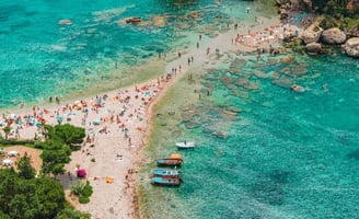 a beach with a boat and people on the water