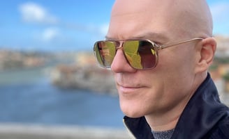 close-up of a bald man in mirror shades 