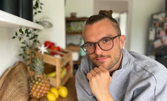 ein mann mit Brille und bart, der in einer Küche vor Gemüse und Obst steht