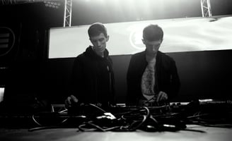 Twins brothers standing in front of a stage with a large screen