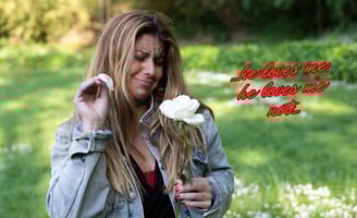 a woman in a denim jacket and plucking petals from a white rose
