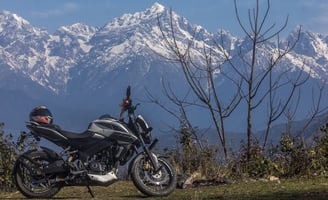 a motorcycle parked on a grassy field with mountains in the background