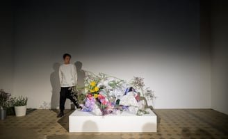 Hedy Leung interacting with the hand-built vessels and green materials during the performance