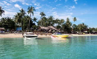 A picturesque beach in Koh Samui, Thailand, with two speedboats docked on the shore and palm trees