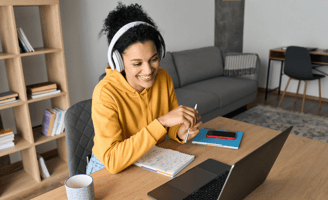 Young woman attending online speech therapy session, wearing headphones and smiling at her therapist
