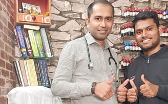 Two men Dr Ansul Sachan and Navneet standing in front of a desk with a laptop