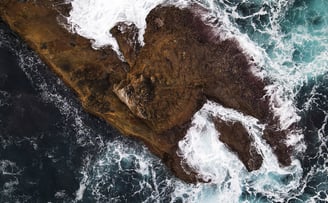 Un îlot est pris en photo du dessus par un drone, les vagues de la mer déferlent sur l'îlot