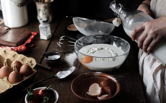 a person is pouring milk into a bowl of eggs