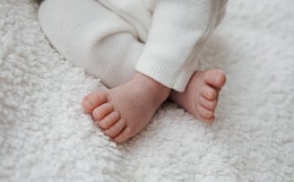 a baby's feet and toes on a white blanket