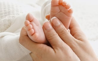 a woman holding a baby's feet up to her feet