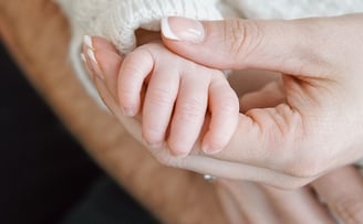 a woman holding a baby's hand while holding a baby's hand