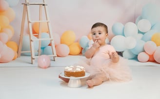 a baby girl in a pink tutu and a cake