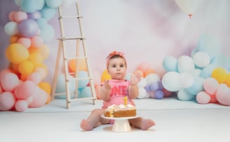 a baby girl sitting on a cake with a cake