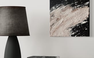 a lamp on a table with books and a abstract painting with natural colors