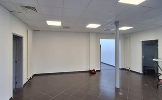 Une photo avant transformation de l'ancien showroom avec des murs blanc et un sol gris