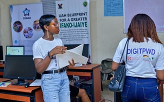 2 girls standing on opposite sides, with one having an inscription on the back of her shirt "DIGITPWD"