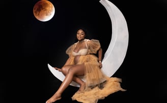 a pregnant woman sitting on a moon shaped moon