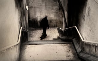 Lone figure walking down a concrete stairwell in a moody urban fine art photograph