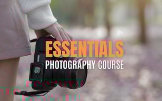 Close-up of a person holding a DSLR camera with text overlay reading Essentials Photography Course.