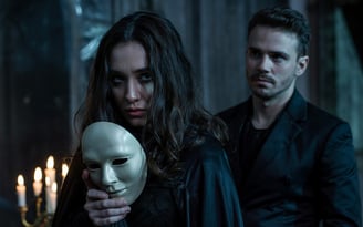 a man and woman in black clothing holding a mask