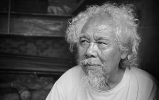 A portrait of an older  Indonesian man with white hair and beard by Peter Pickering